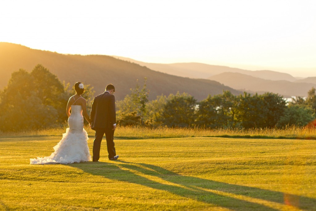 Walking across sun soaked fields during golden hour. Cumbria Wedding photographer Karli Harrison Photography