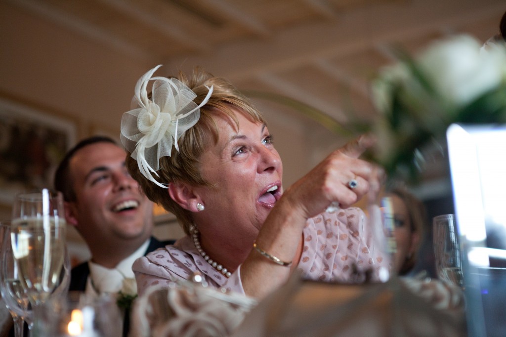 Mother of the groom laughing and pointing to best man during speeches
