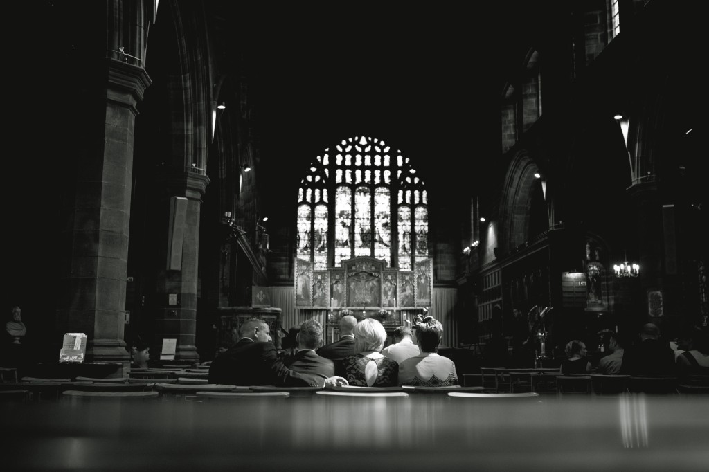 A beam of sunlight falls on wedding guests as they wait in the church for the bride. Wedding Photography Lancashire