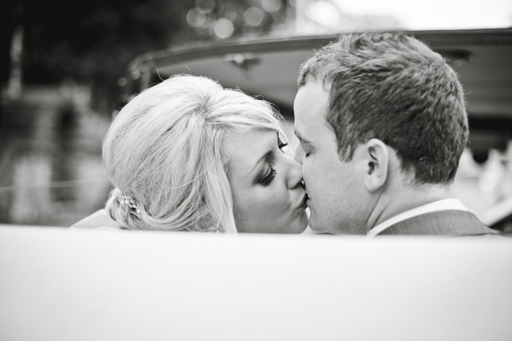 Sharing a kiss in the wedding car, a bride and groom share a tender moment perfect for wedding photography