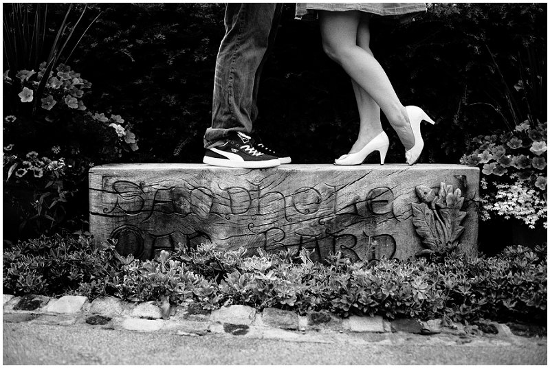 Engaged couple stand on sign at Sandhole Oak Barn Cheshire Wedding Photography