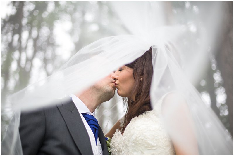 Beautiful bride and groom kiss under veil at Abbey House Hotel Wedding
